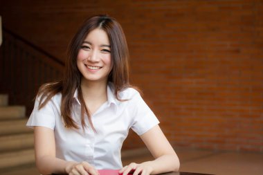 Taylandlı yetişkin öğrenci üniforması portresi. Güzel kız rahatla ve gülümse.