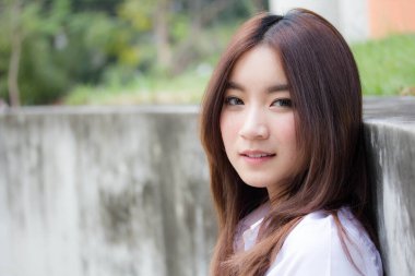 Taylandlı yetişkin öğrenci üniforması portresi. Güzel kız rahatla ve gülümse.