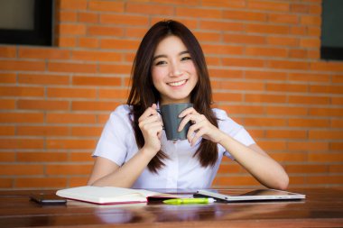 Taylandlı yetişkin öğrenci üniformasının portresi. Güzel kahve içiyor.