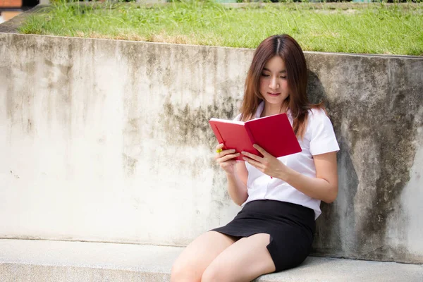 Taylandlı yetişkin öğrenci üniforması portresi. Güzel kız kırmızı kitabı okudu.