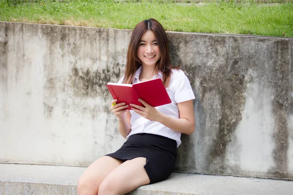 Taylandlı yetişkin öğrenci üniforması portresi. Güzel kız kırmızı kitabı okudu.