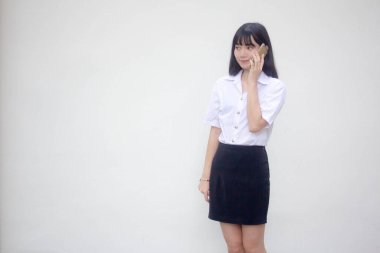 Yetişkin öğrenci üniforması. Güzel bir kız. Akıllı telefondan arıyor.