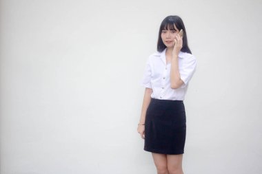 Yetişkin öğrenci üniforması. Güzel bir kız. Akıllı telefondan arıyor.