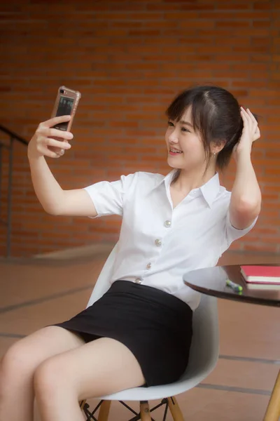 タイのポートレート大人学生大学制服美しいです女の子使用して彼女のスマートフォンSelfie — ストック写真