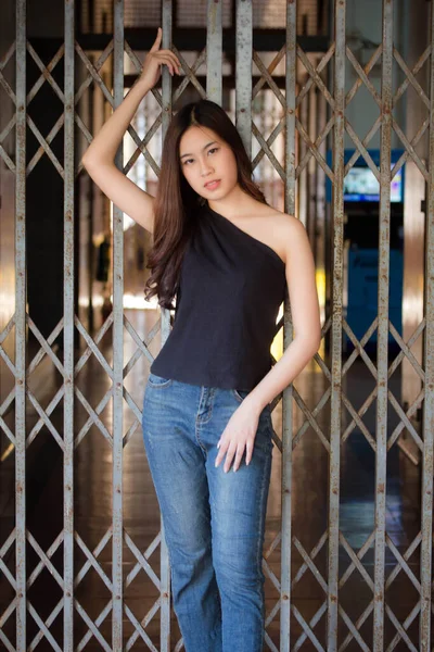 泰国人的画像中国成年人漂亮的女孩黑色衬衫蓝色牛仔裤放松微笑 — 图库照片