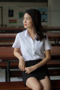 Taylandlı yetişkin öğrenci üniforması güzel kız rahatla ve gülümse.