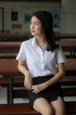 Taylandlı yetişkin öğrenci üniforması güzel kız rahatla ve gülümse.