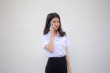 Yetişkin öğrenci üniforması. Güzel bir kız. Akıllı telefondan arıyor.