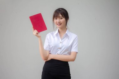 Taylandlı yetişkin öğrenci üniforması güzel kız kırmızı kitap gösteriyor.