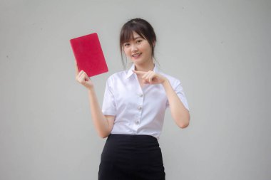 Taylandlı yetişkin öğrenci üniforması güzel kız kırmızı kitap gösteriyor.