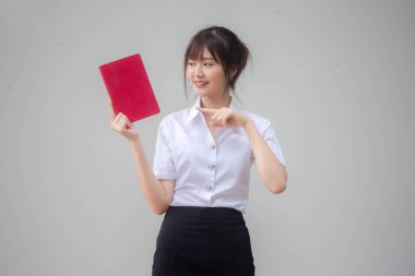 Taylandlı yetişkin öğrenci üniforması güzel kız kırmızı kitap gösteriyor.