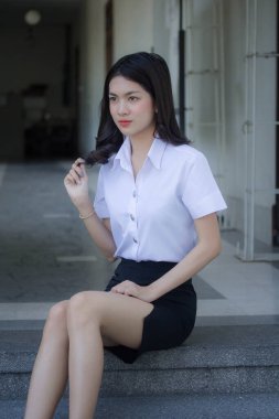 Taylandlı yetişkin öğrenci üniforması güzel kız rahatla ve gülümse.