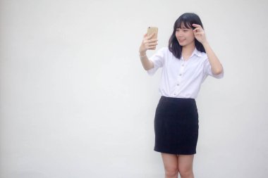 Yetişkin öğrenci üniforması güzel kız akıllı telefonuyla selfie çekiyor.