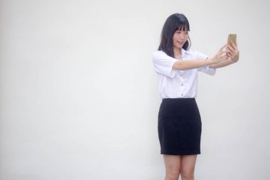 Yetişkin öğrenci üniforması güzel kız akıllı telefonuyla selfie çekiyor.