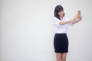 Yetişkin öğrenci üniforması güzel kız akıllı telefonuyla selfie çekiyor.