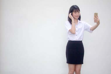 Yetişkin öğrenci üniforması güzel kız akıllı telefonuyla selfie çekiyor.