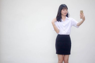 Yetişkin öğrenci üniforması güzel kız akıllı telefonuyla selfie çekiyor.