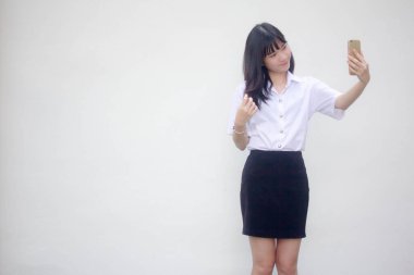 Yetişkin öğrenci üniforması güzel kız akıllı telefonuyla selfie çekiyor.