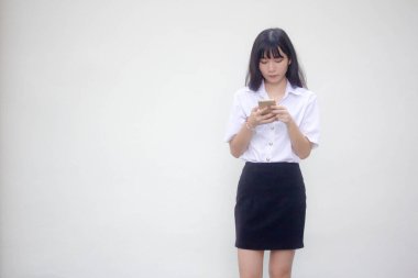 Yetişkin öğrenci üniforması. Akıllı telefonunu kullanan güzel bir kız.