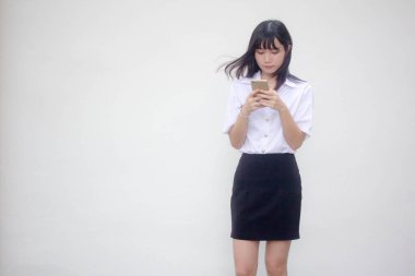 Yetişkin öğrenci üniforması. Akıllı telefonunu kullanan güzel bir kız.