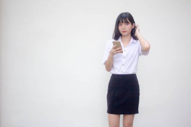 Yetişkin öğrenci üniforması. Akıllı telefonunu kullanan güzel bir kız.