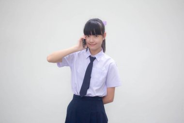 Thai Ortaokulu öğrencisi üniforması güzel kız akıllı telefonu arıyor.