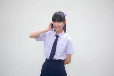 Thai Ortaokulu öğrencisi üniforması güzel kız akıllı telefonu arıyor.