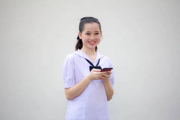 アジアタイ中学生制服美少女彼女の電話と笑顔を使用して — ストック写真