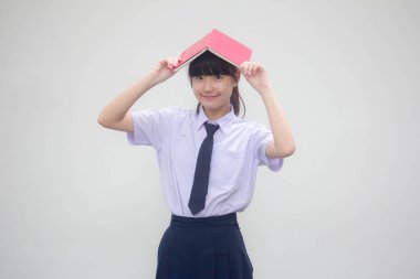 Asya Thai ortaokulu öğrencisi üniforması güzel bir kız ve bir kitap.