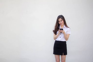 Yetişkin öğrenci üniforması. Güzel bir kız. Telefonunu kullanıp gülümsüyor.