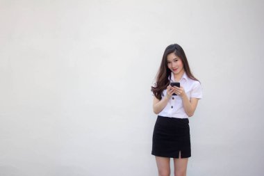 Yetişkin öğrenci üniforması. Güzel bir kız. Telefonunu kullanıp gülümsüyor.