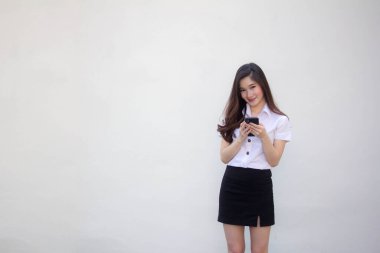 Yetişkin öğrenci üniforması. Güzel bir kız. Telefonunu kullanıp gülümsüyor.