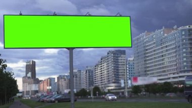 Konsepti uydur. Şehir yolunda akşam gökyüzünün arka planına karşı yeşil ekran reklam panosu.