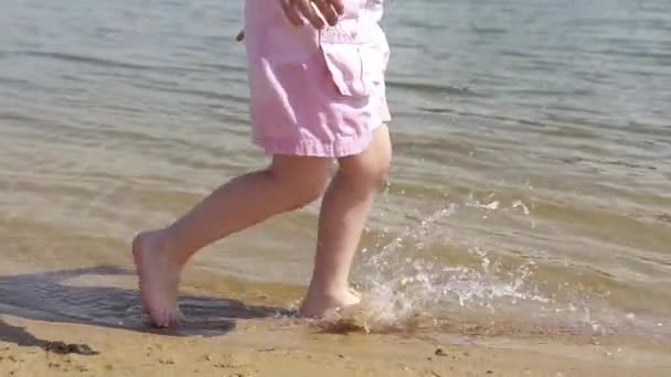 穿着粉红短裙 嬉闹嬉闹的年轻高加索女孩在海滩的白沙滩上奔跑 孩子的脚在沙滩上奔跑 — 图库视频影像