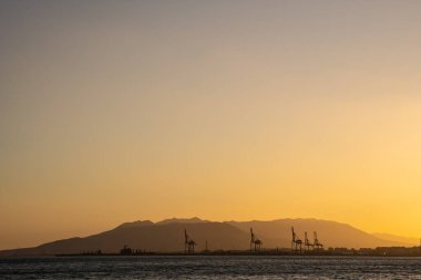 Yaz batımı. Denizin üzerinde turuncu gökyüzü, ufukta kopya alanı olan dağlar..