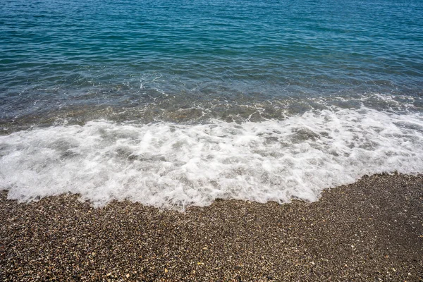 泡沫浪涌上平静的海滩 沙滩上撒满了沙子和卵石 前视图复制空间 — 图库照片