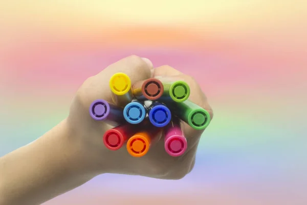 Gökkuşağı arka planında renkli işaretlerle el ele tutuşmak. Yukarıdan görünüm.