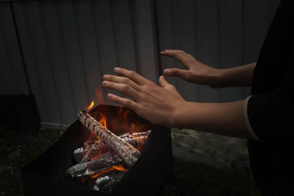 Protestocu adam sokakta ellerini ateşin üzerinde ısıtıyor. Karanlık anahtarda..