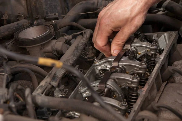 hand checks engine valves in old car.