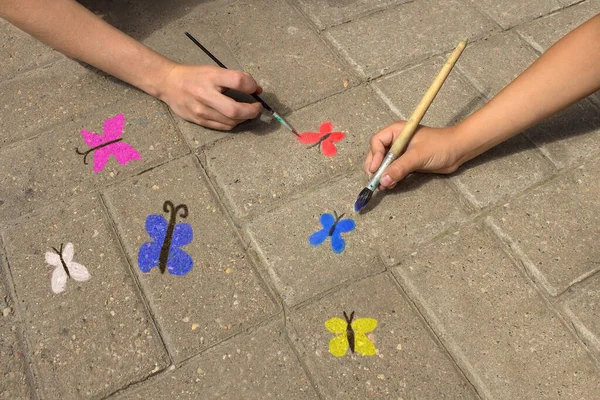 Renkli kelebekler kaldırımda fırçalı çocuklar tarafından çizilir..