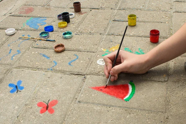 Çocuğun eli kaldırıma bir karpuz çizer. Yaz konsepti.