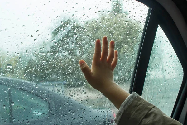 Yağmur damlalarında arabanın camında çocuğun eli var..