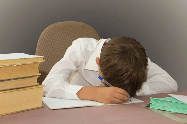 Yorgun, sıkılmış okul çocuğu masasında yatıyor..