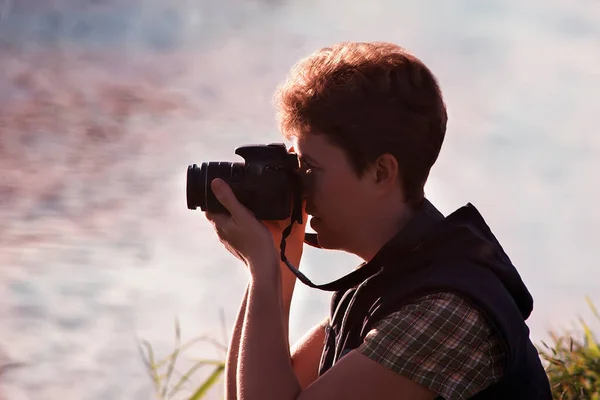 Suyun arka planında elinde kamera olan bir kadın fotoğrafçının silueti..