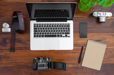 Dizüstü bilgisayar, kamera, film, not defteri boş ve akıllı telefon ahşap masa üstü görünümü ve kopyalama alanı