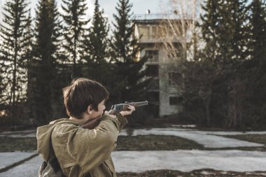 Çocuk dürbünden nişan alıyor. Koruyucu ceketli silahlı bir adam terk edilmiş bir binanın önünde duruyor. Kocaman bir havaalanı binası. Kıyamet sonrası bir dünyada bir avcı..