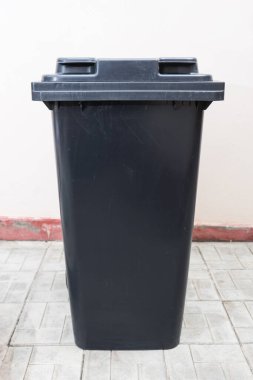 Duvarın yanındaki çöp tenekesini kapat.
