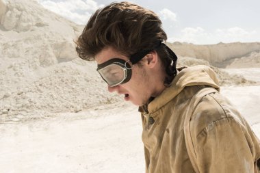 Beyaz kumların arasında bir adamın yüzüne yakın çekim. Yüzünde ter var. Kıyamet sonrası dünyada takipçi bir sapık..