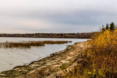 Gölün etrafındaki sonbahar renklerinde güneş batıyor. Battleford İl Parkı, Saskatchewan, Kanada