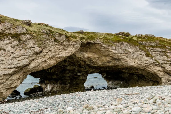 Dalgalar çekildiğinde deniz yığınları ve mağaralar. Arches Provincial Park, Newfoundland, Kanada